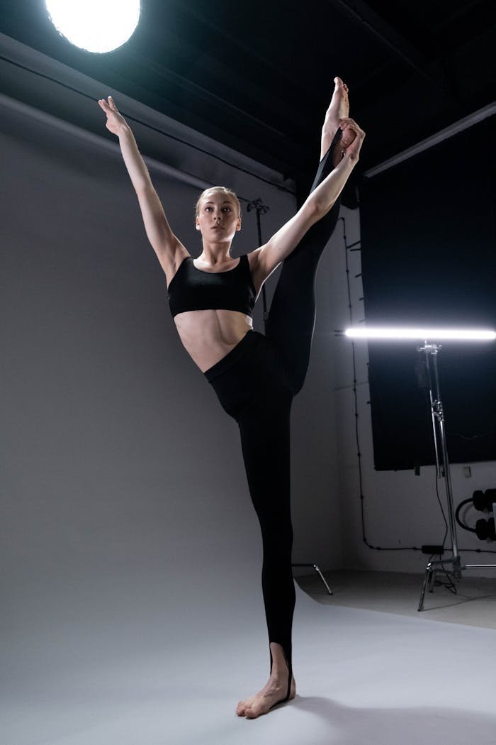 A skilled ballet dancer demonstrates a high leg stretch in a professional studio setting.